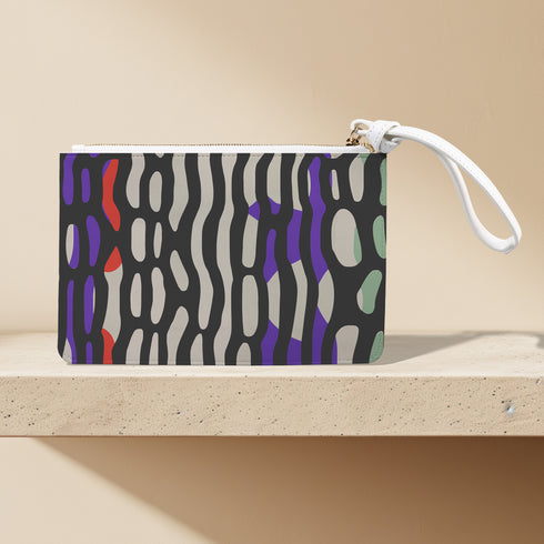 Rectangular wristlet clutch bag with psychedelic black, purple, red, and green pattern. White wrist strap and gold zipper visible